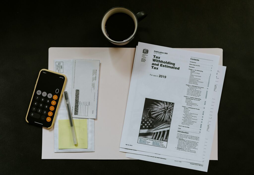 A calculator, pen, envelopes, tax documents, and a cup of coffee are arranged on a desk with a black background—an ideal setup for handling a Mortgage Alert.