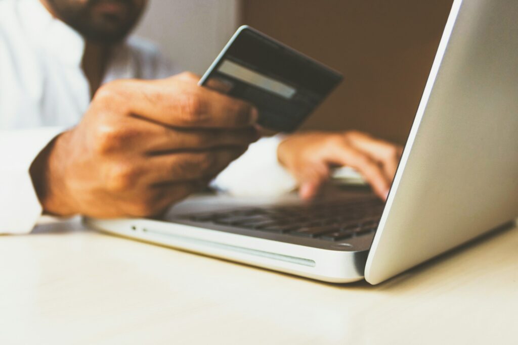 A person holds a credit card in one hand while typing on a laptop with the other, enjoying the stress relief and relax of convenient online shopping or payment.