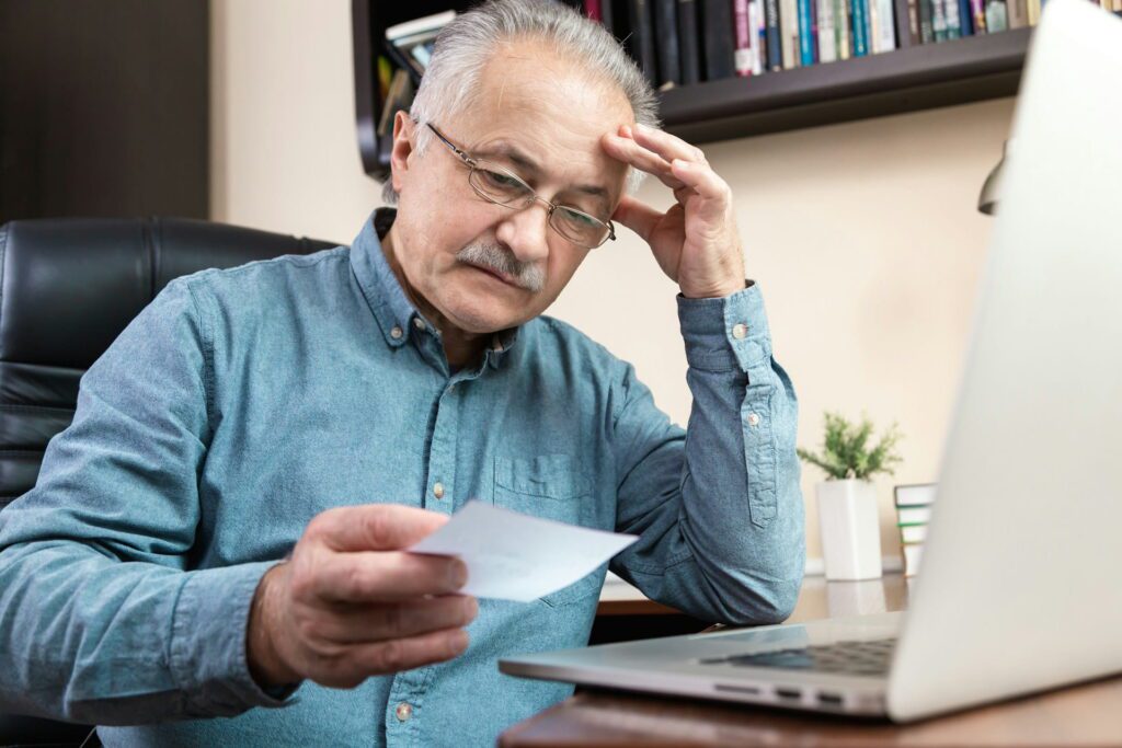 Retired man reviewing financial documents on laptop while planning pension finances